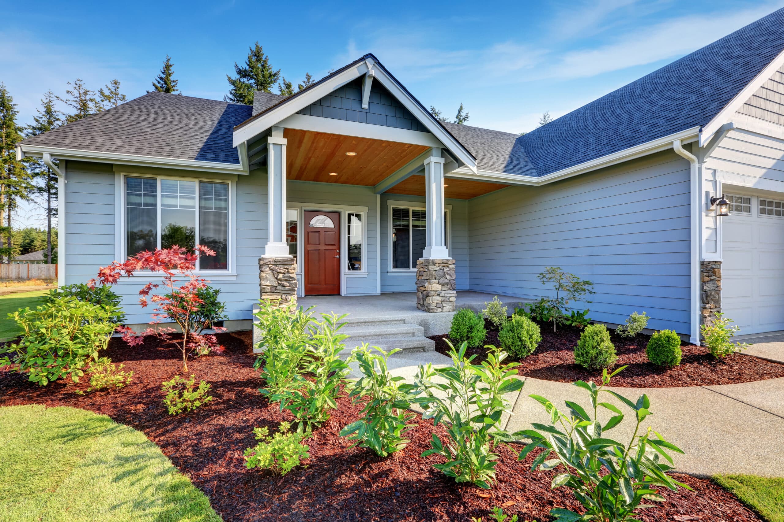 Light blue siding house . Porch with stone base columns