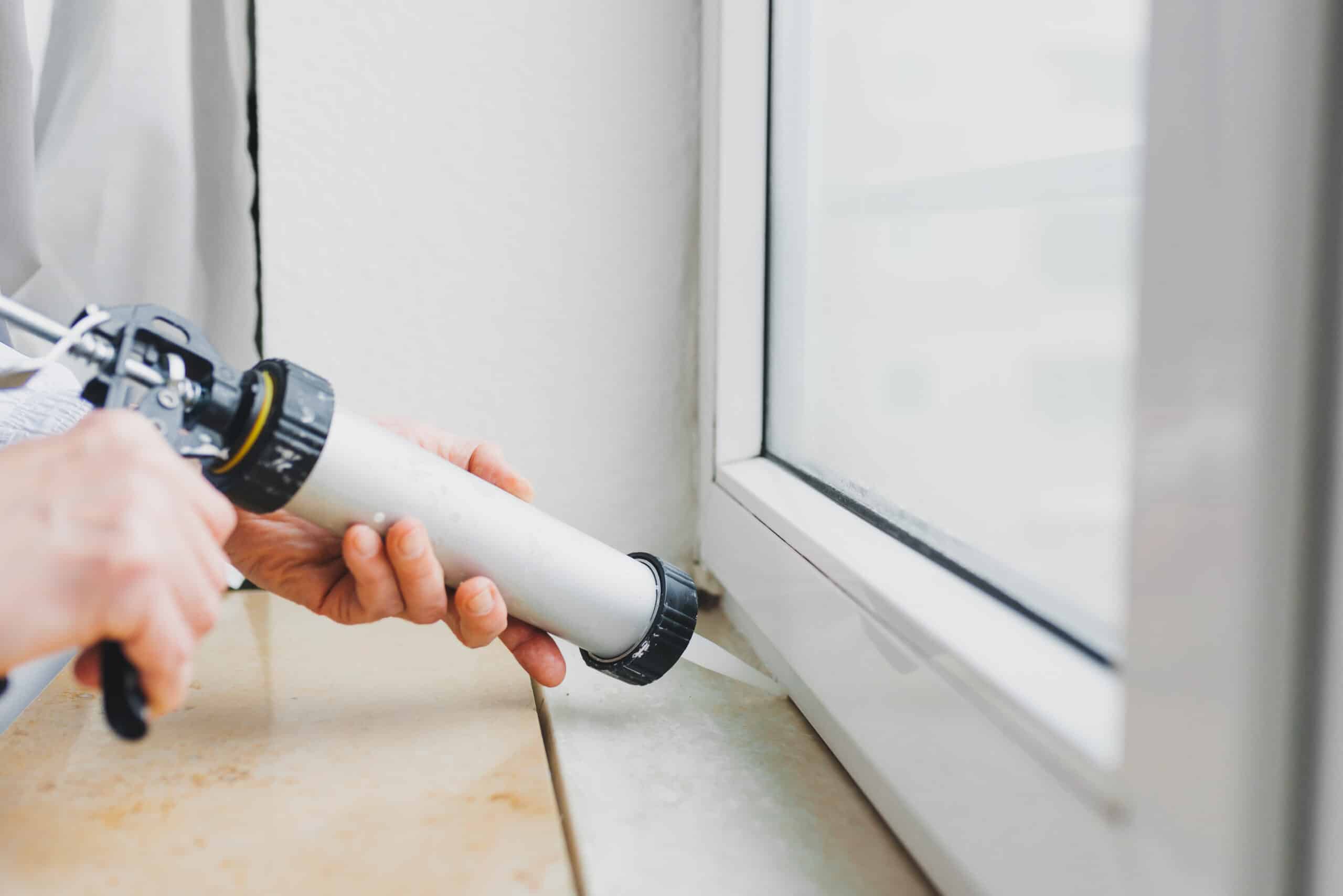 Hands of worker using a silicone tube for repairing of window