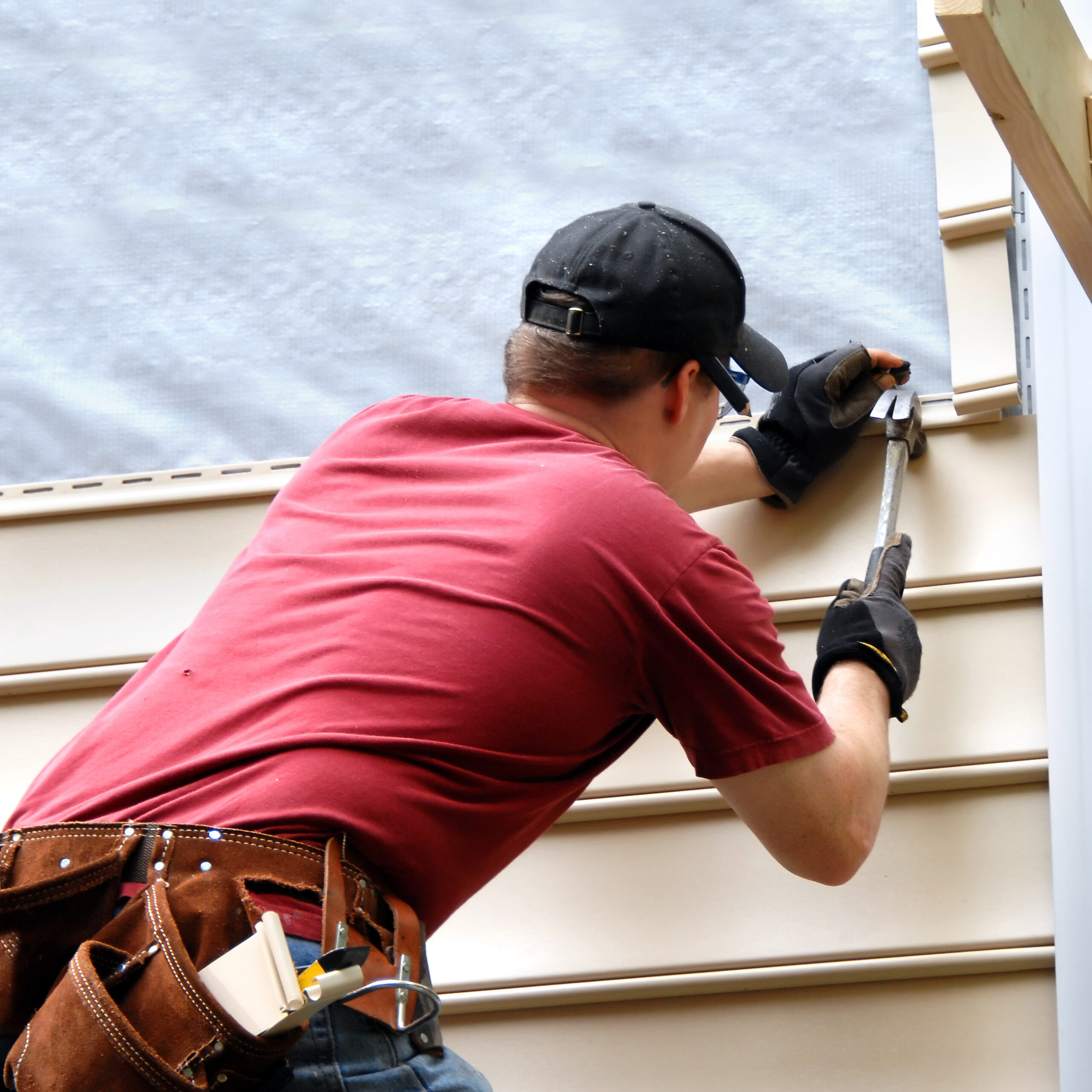 worker installing siding on home