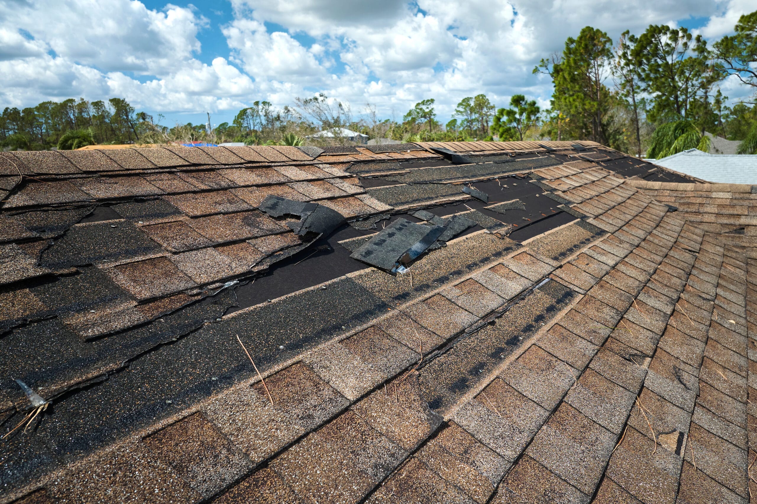 Damaged house roof with missing shingles after hurricane Ian in Florida. Consequences of natural disaster