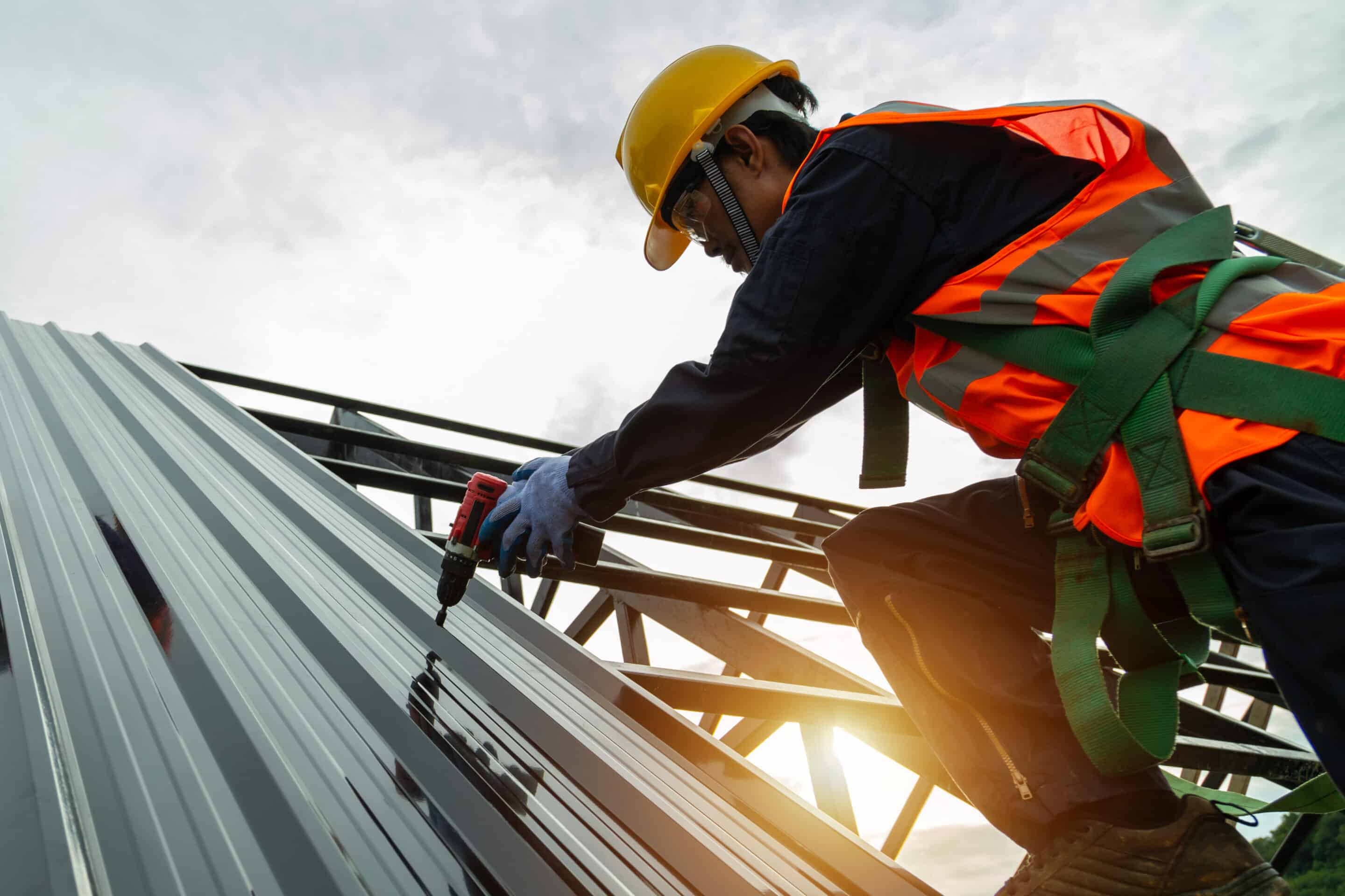 Roof construction, Asian worker install new roof, Roofing tools electric drill used on new roofs with metal sheet in the construction site. Roof construction, Asian worker install new roof, Roofing tools electric drill used on new roofs with metal sheet in the construction site.