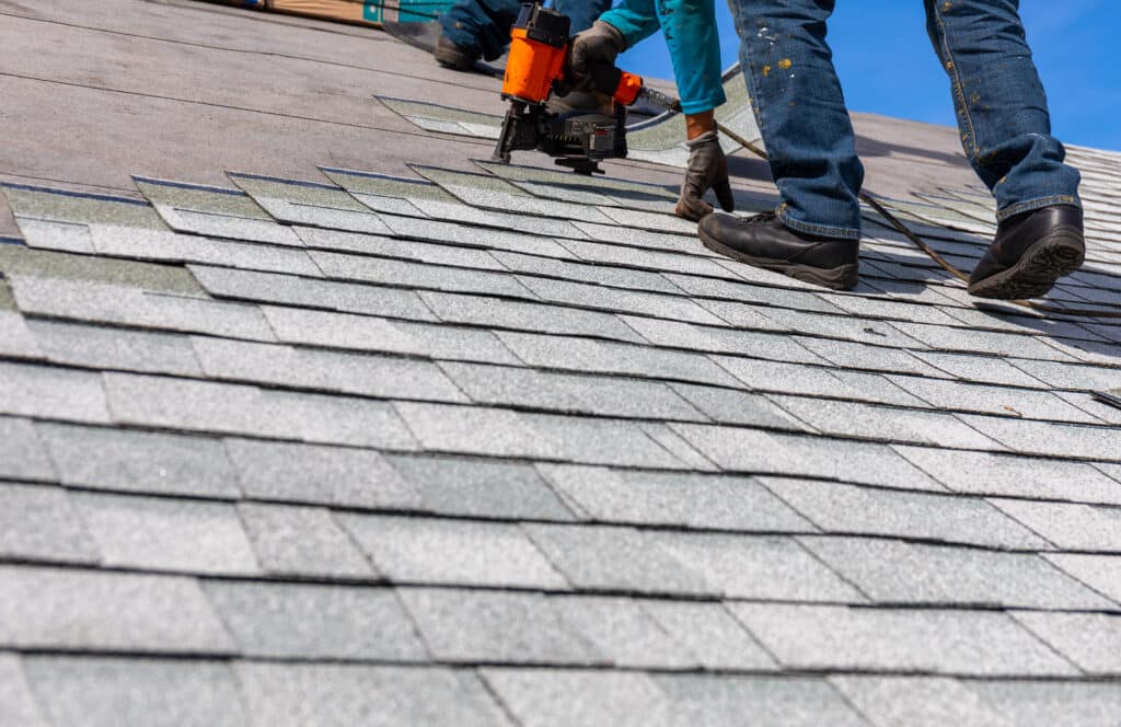 roofing industry roofer installing roof shingles with pnuematic roofing nailer